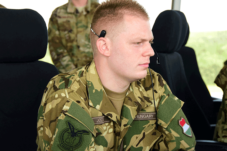 Hungarian air force Warrant Officer wearing headset sitting at his computer.