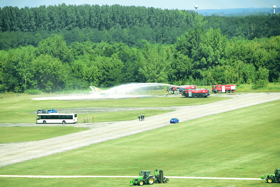 Travel bus of service members watch firetrucks spray aircraft during in an in-flight emergency response exercise.
