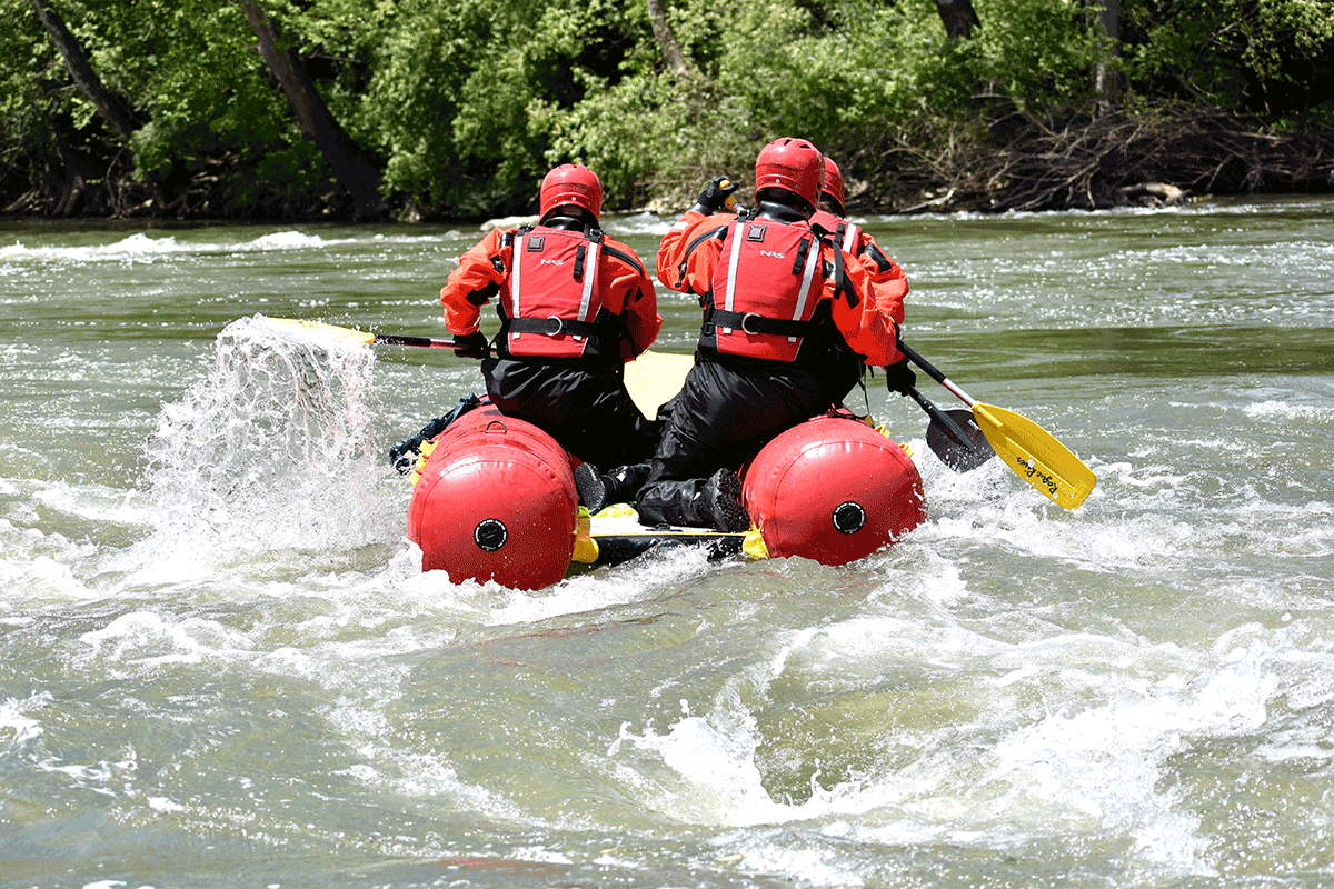 Firefighters paddle a raft.