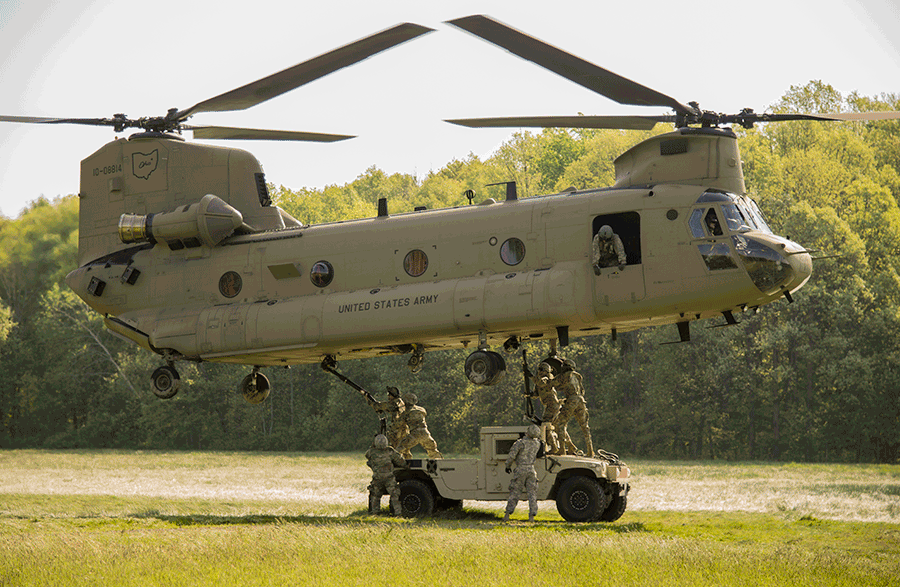 Soldiers connect a vehicle load beneath a CH-47 Chinook helicopter.