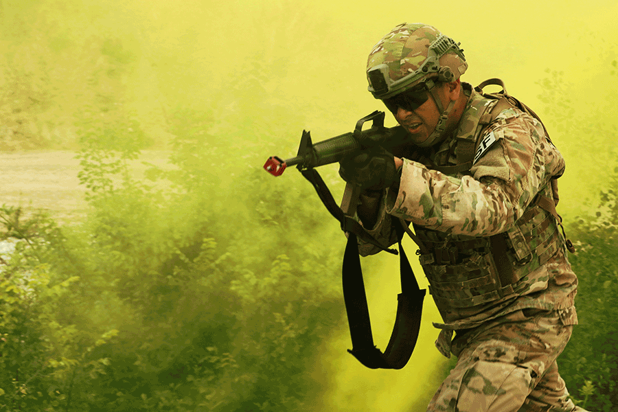 Armed Soldier walks through green smoke.