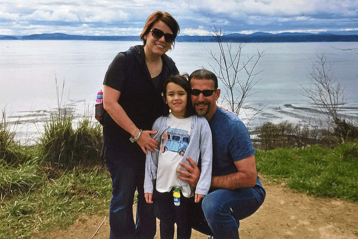 Family photo of Ortiz, husband, and daughter at a lake.