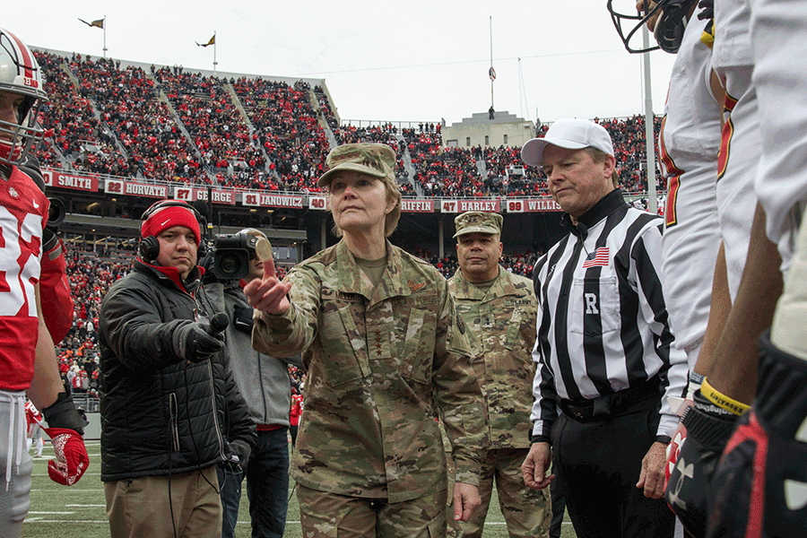 U.S. Air Force Gen. Maryanne Miller tosses the coin mid field with captains, refs, medai and Maj. Gen Harris gather around.