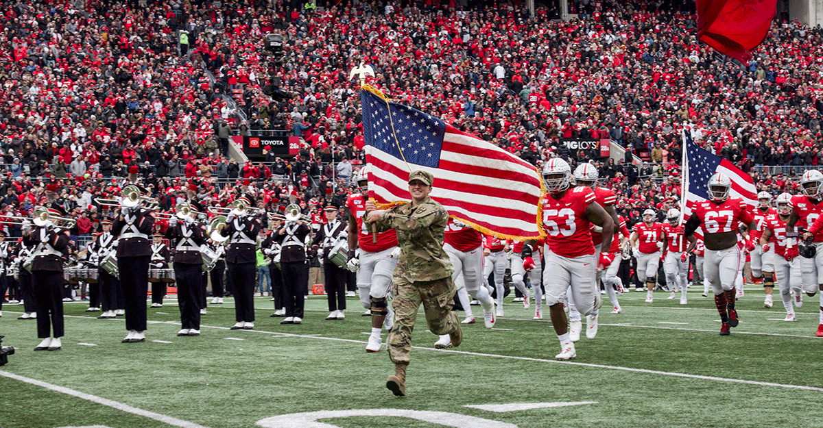 Sgt. Whitney Schalk carries the American flag as she leads The Ohio State University football team out onto the field.