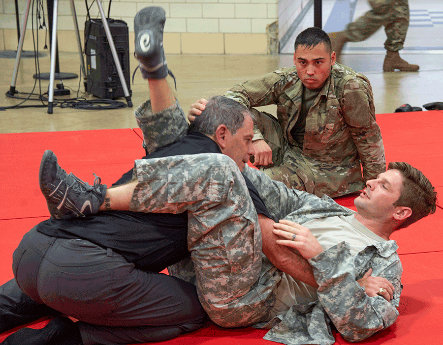 Retired U.S. Army Lt. Gen. Mike Ferriter works on techniques with a couple of competitors on mat. 