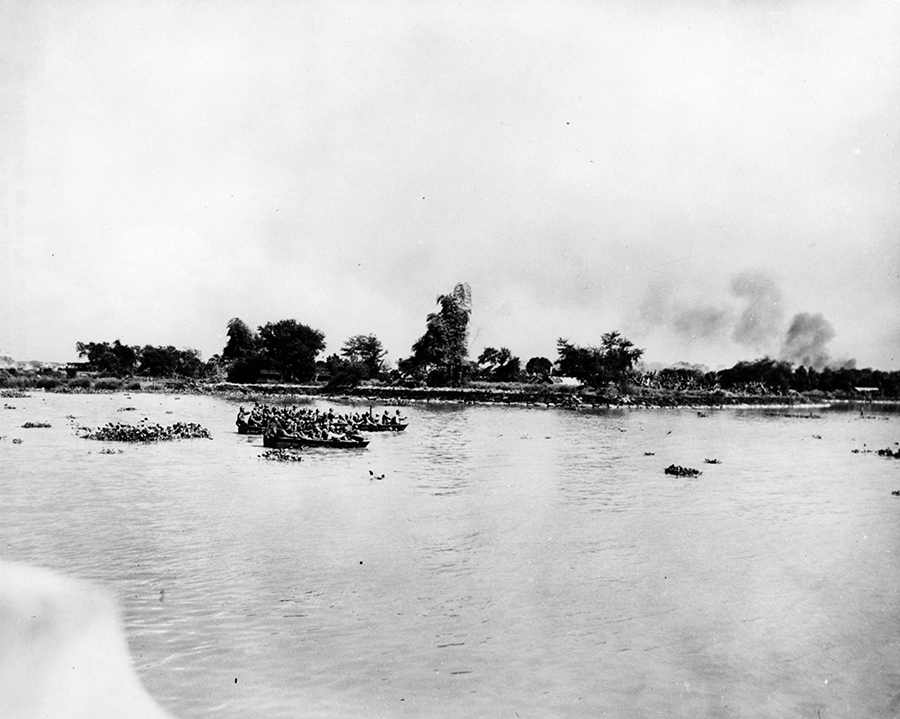Soldiers in plywood assault boats across river. 