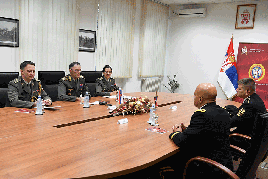 Maj. Gen. John C. Harris Jr. and Command Sgt. Maj. William Workley sit at table with members of the Serbian Armed Forces.