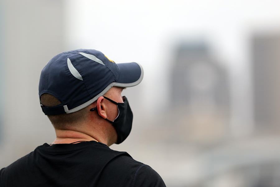 Profile of male in ballcap with city blurred in background.