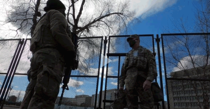 Still from video- Two guard members patrol fenced area. 