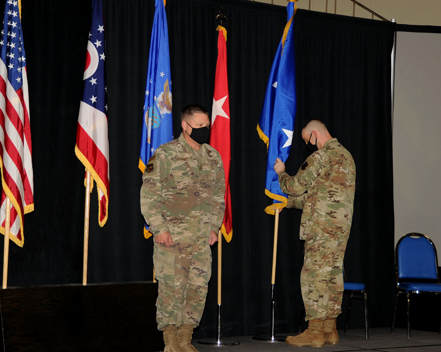 Maj. Gen. James R. Camp stands at attention while Master Sgt. Matthew Dill places the general’s two-star flag in its base.