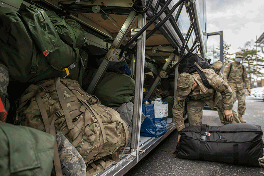 Soldier get bags from below the bus.