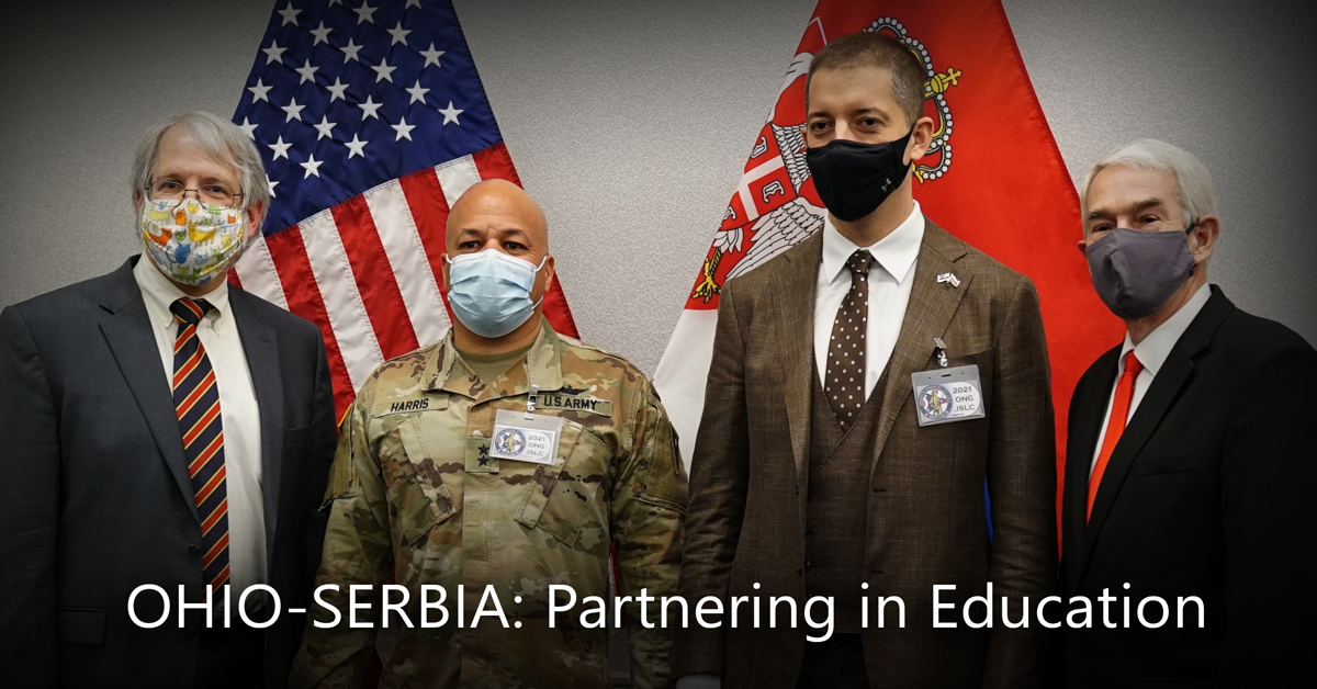 Leadership wearing masks pose in front of flags.