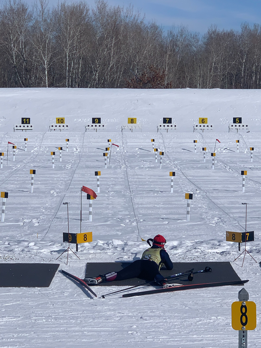 Guardmember on mat on snow-covered ground shoots at targets.