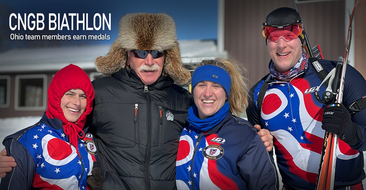 Male coach with 3 biathlon team members wearing Ohio flag jackets.