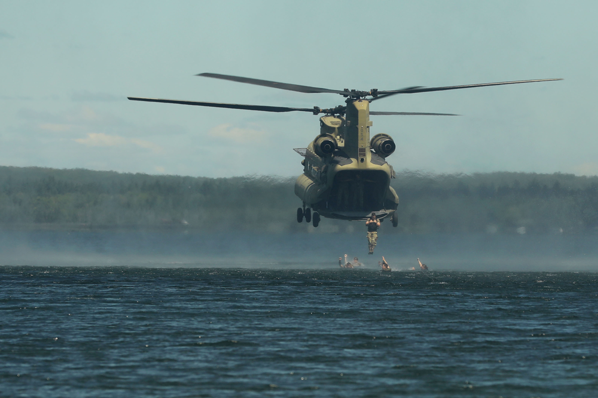 Soldiers jump into water from helicopter.