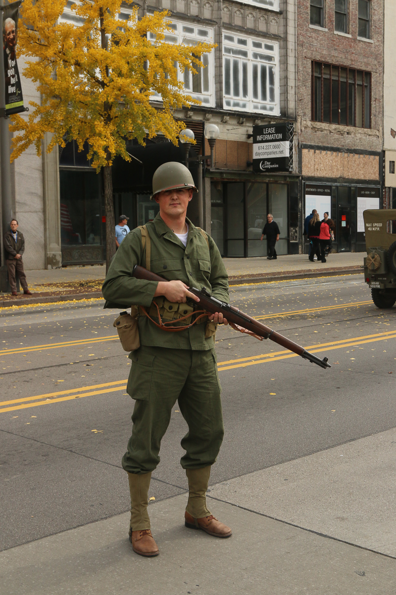 Mann marching in vintage uniform in parade.