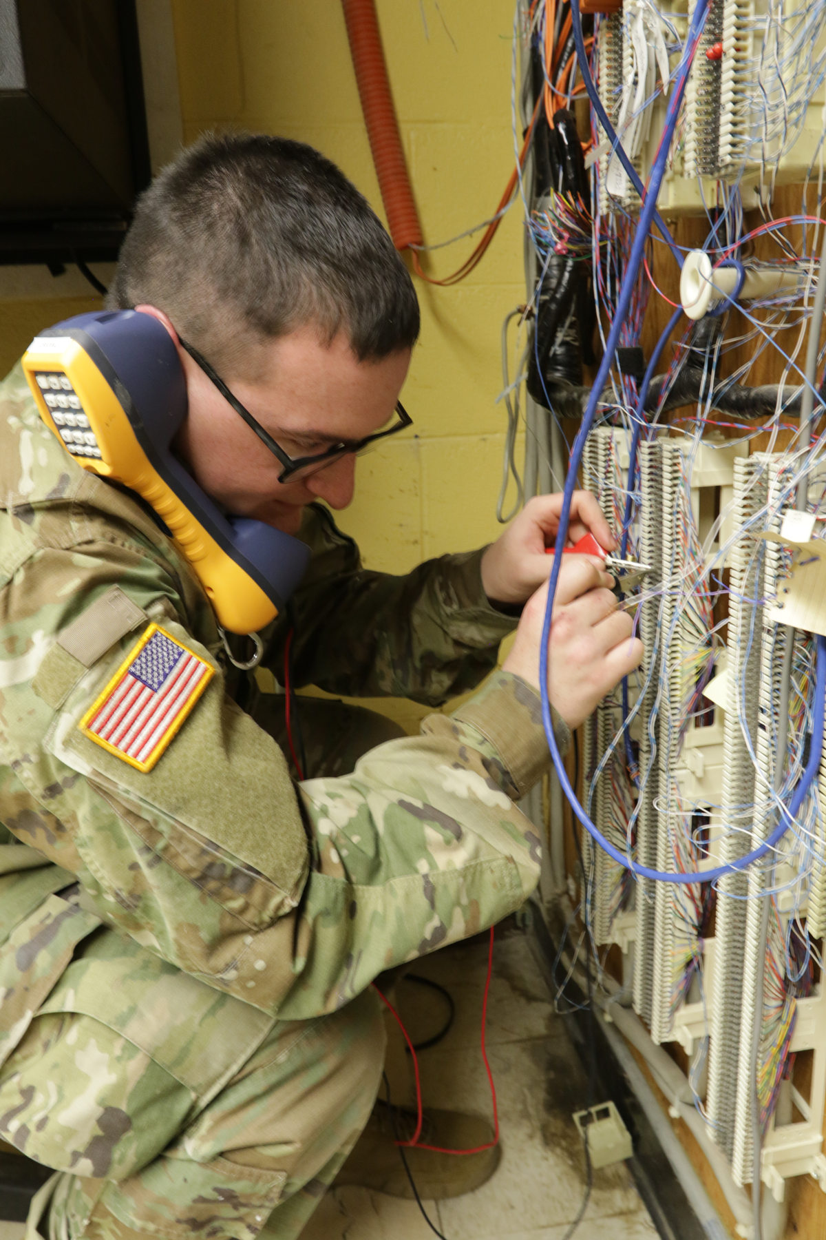 Soldier working on wall of network cables
