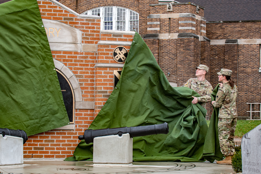 Two soldiers unveil tarp over memorial.