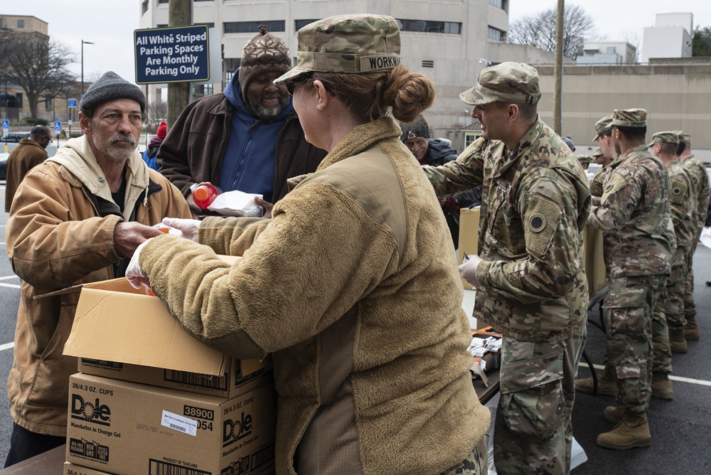 Soldiers hand dinners to citizens in need.