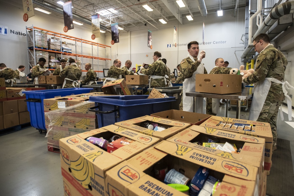 Soldiers load boxes in warehouse.
