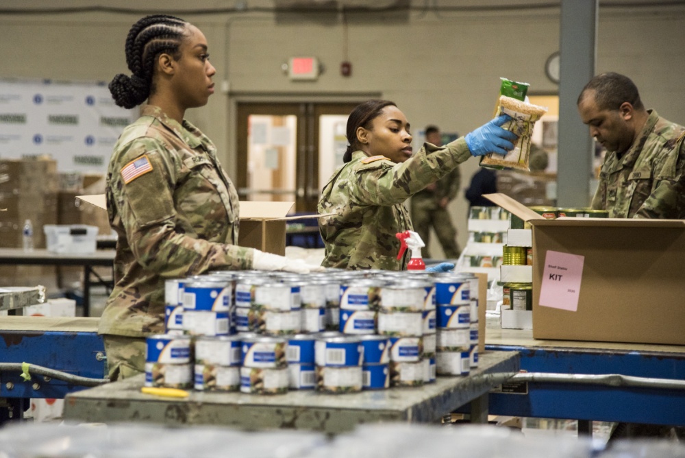 Soldiers load boxes with canned goods.