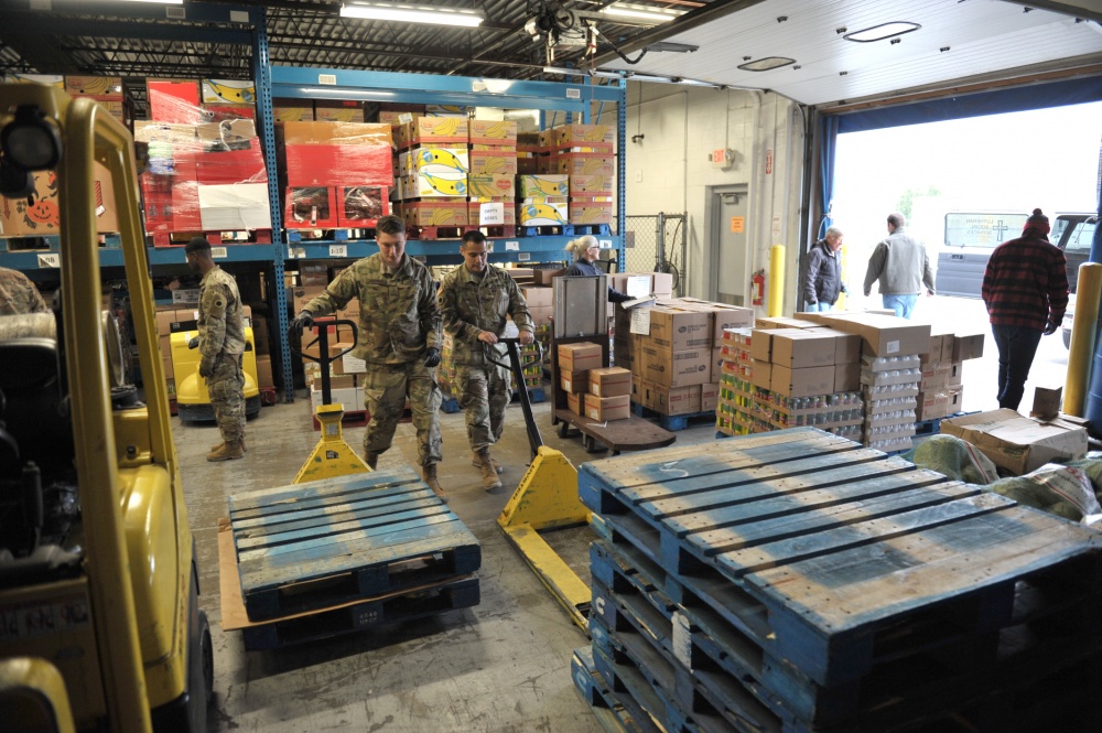 Soldiers load pallets inwarehouse.