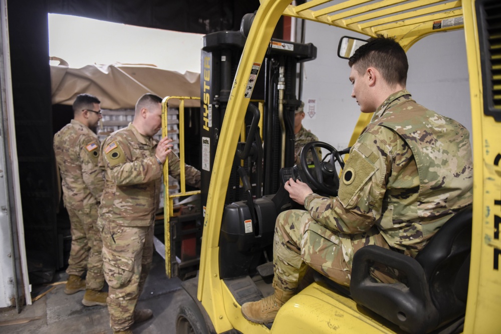 Soldiers load pallets onto trolly.