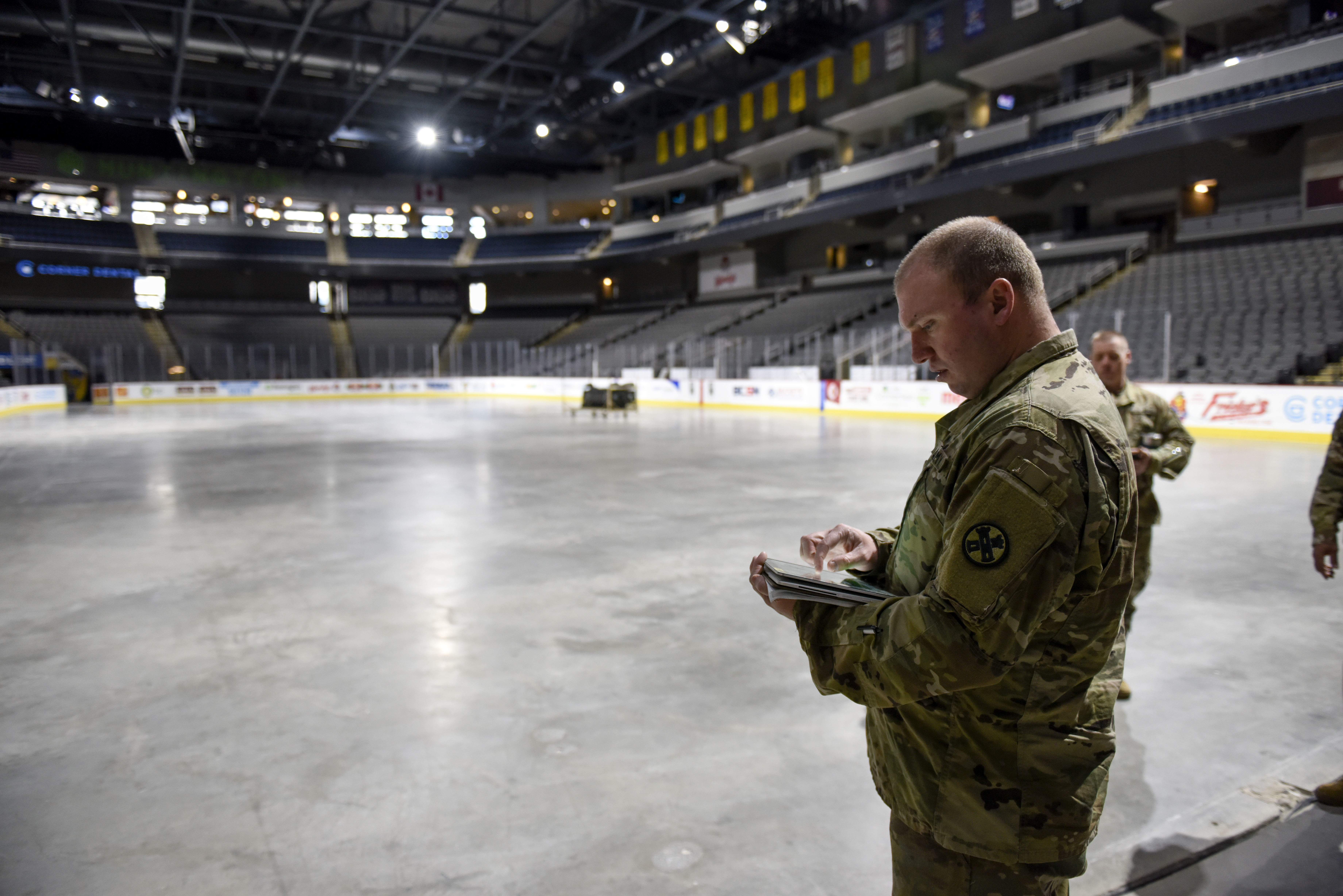 Guard members inputs info on hand-held device in hockey arena.