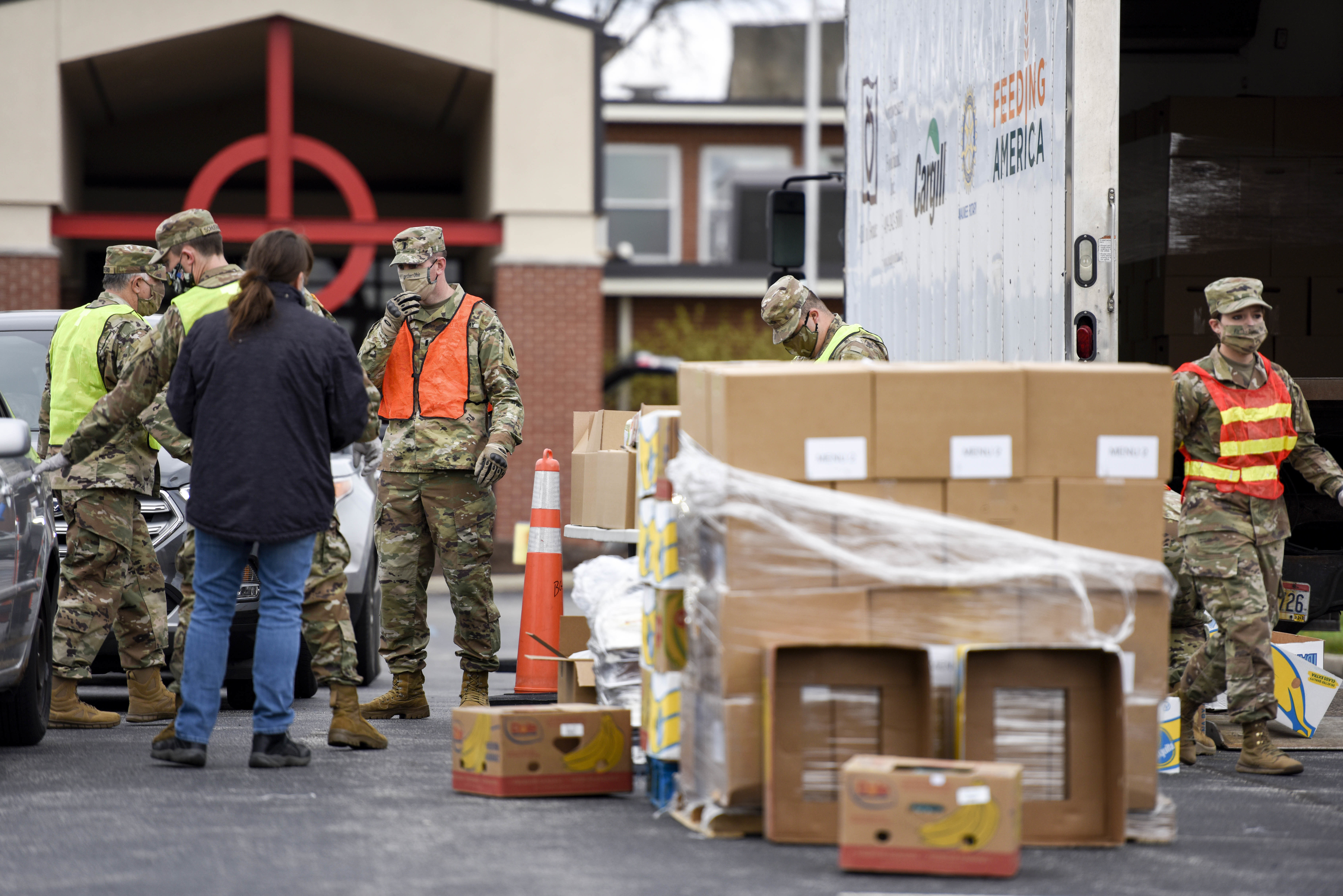 Soldiers gather boxes around semi trailer for distribution.