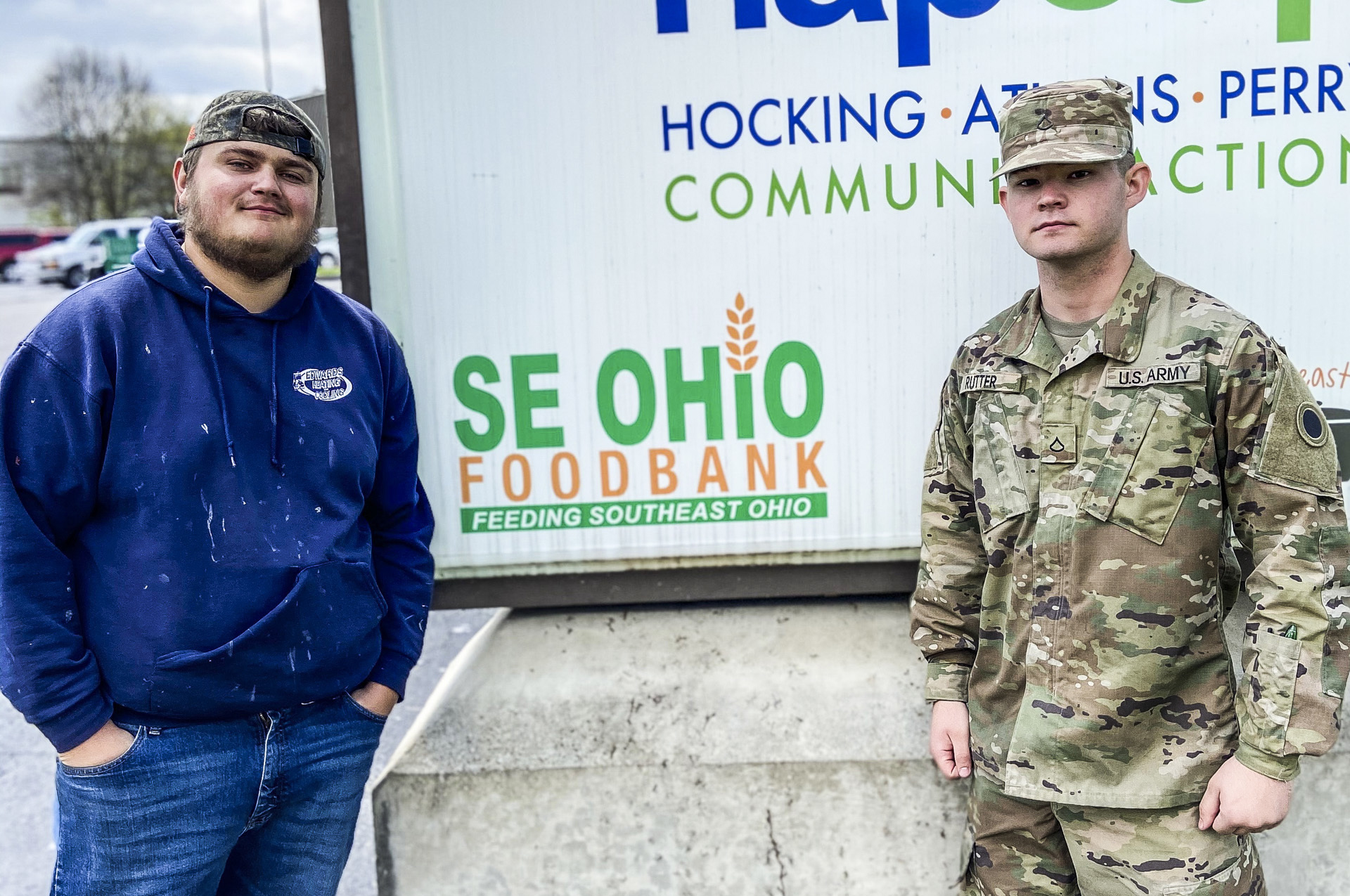 Soldier stands with man in front of food bank sign