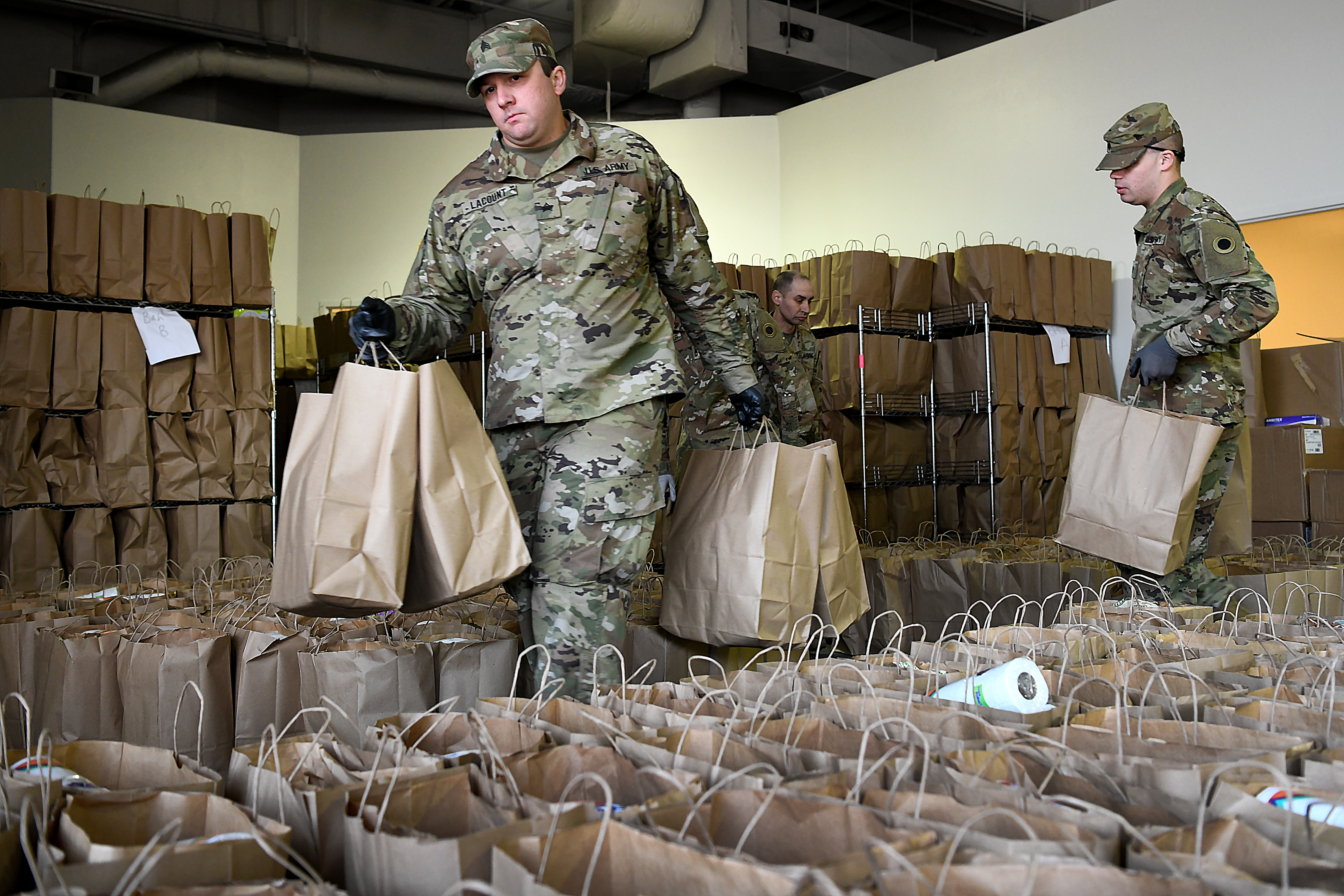 Soldiers gather bags of groceries.