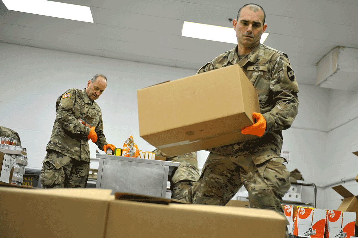 Soldier load boxes on pallet in warehouse.
