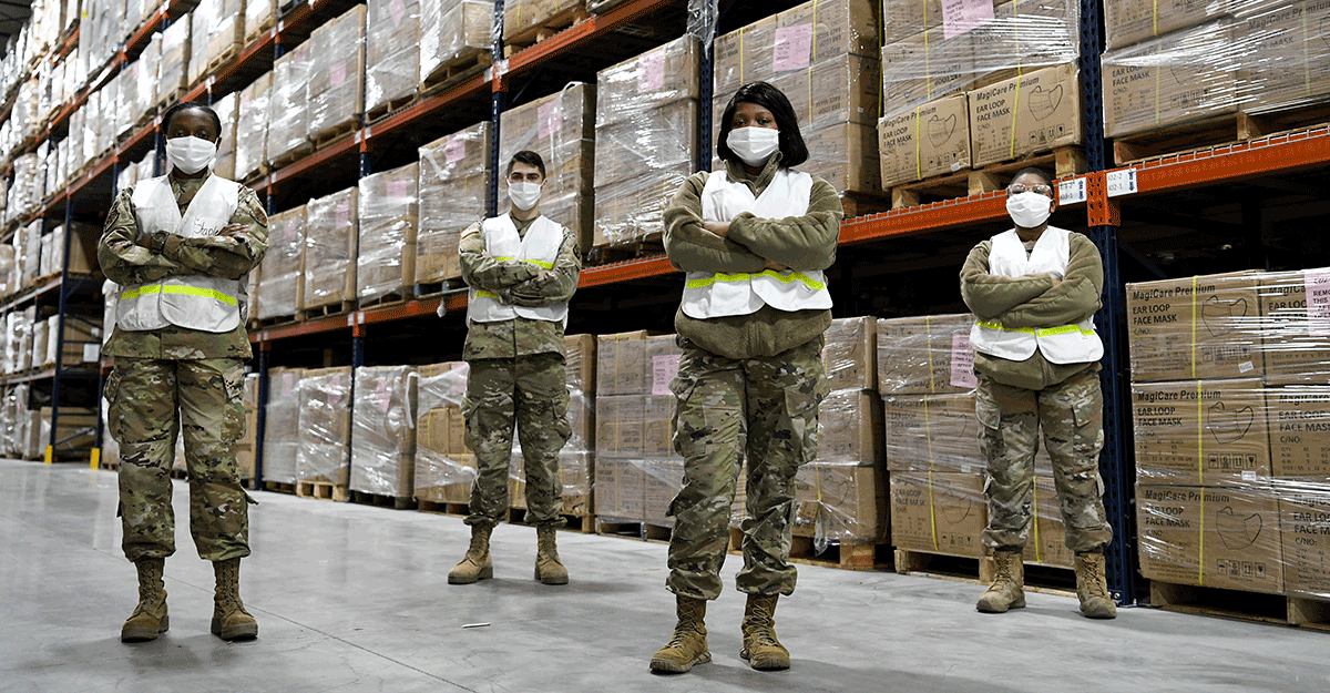 Four members in masks in warehouse.