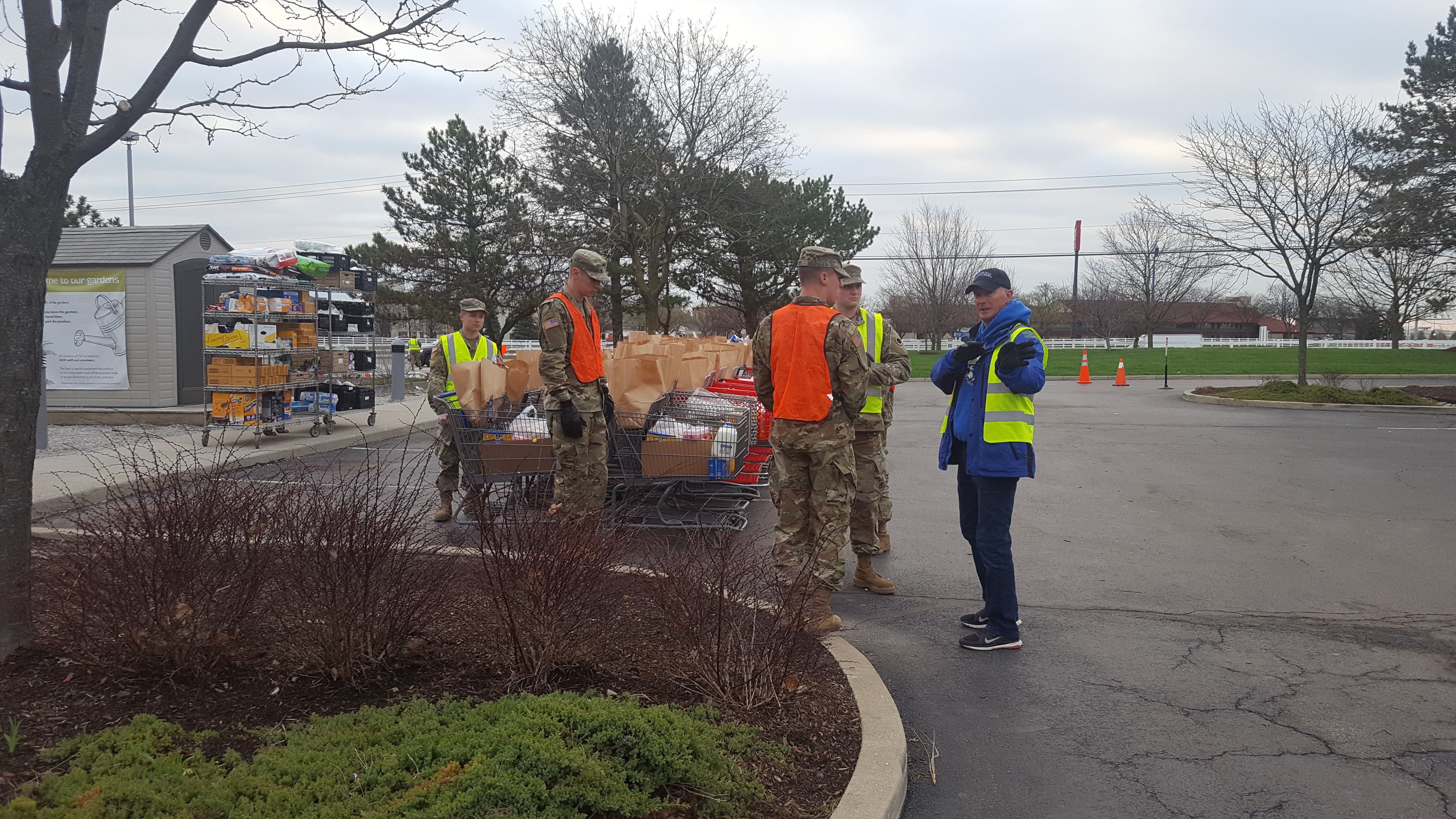 Soldiers prepare to hand out groceries in parking lot with lined up grocery carts.