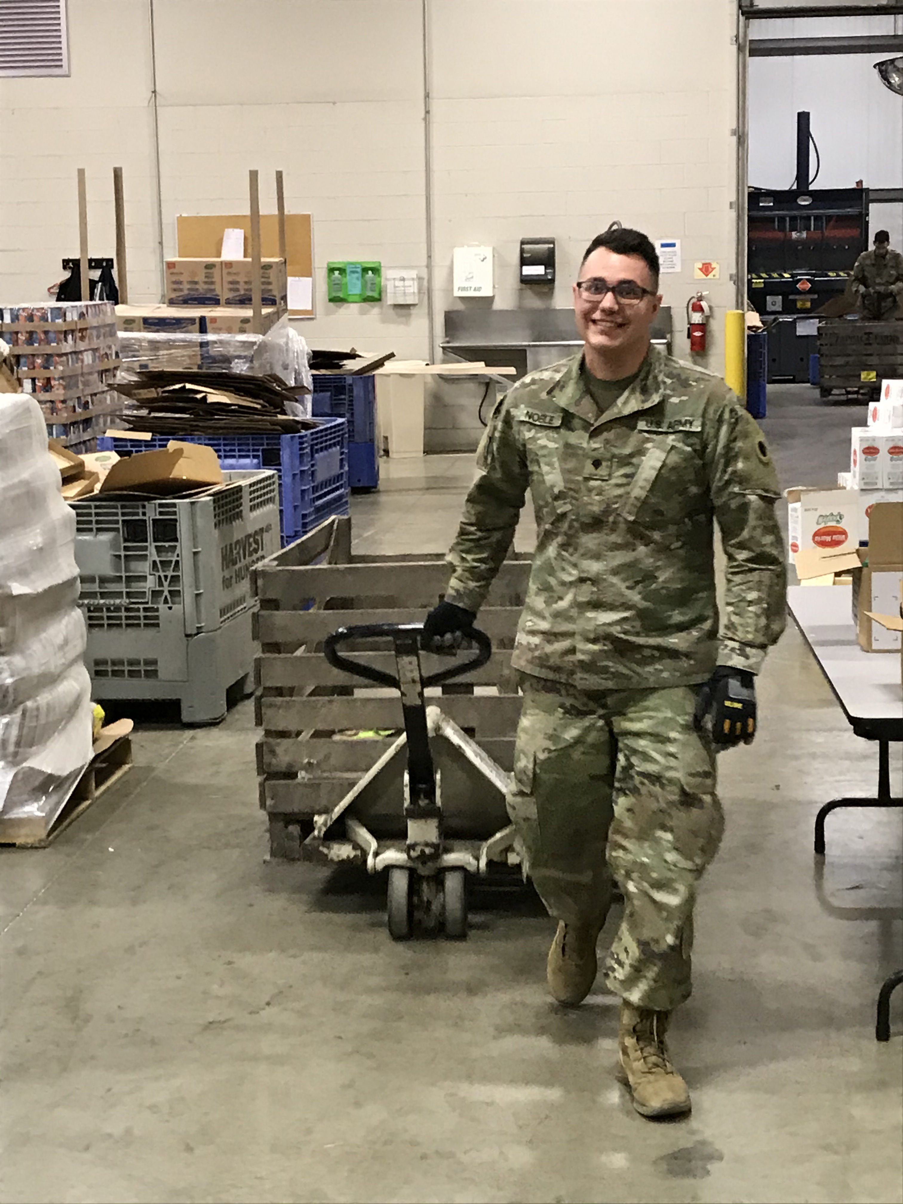 Soldier moves a pallet of food with a pallet jack.