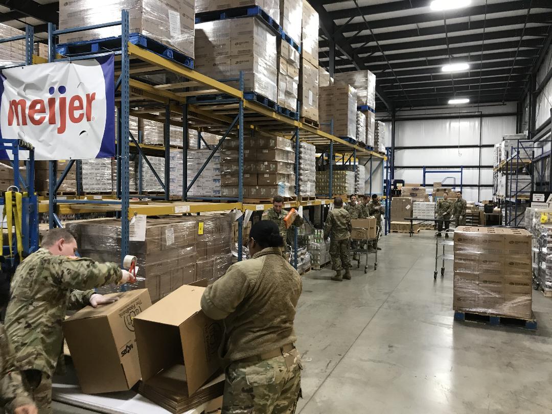 Soldiers unpack boxes in warehouse.