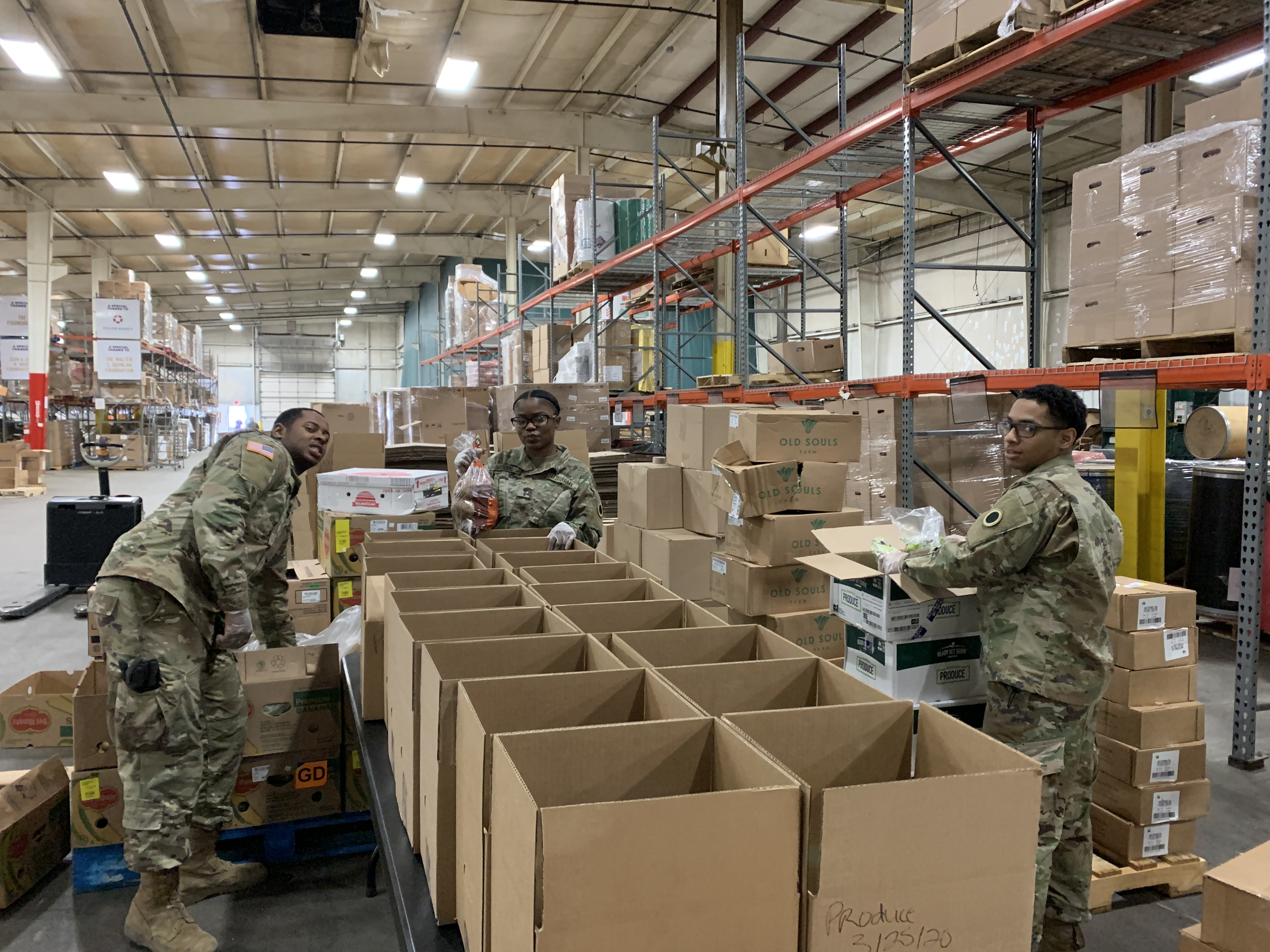 Soldiers pack boxes with produce.