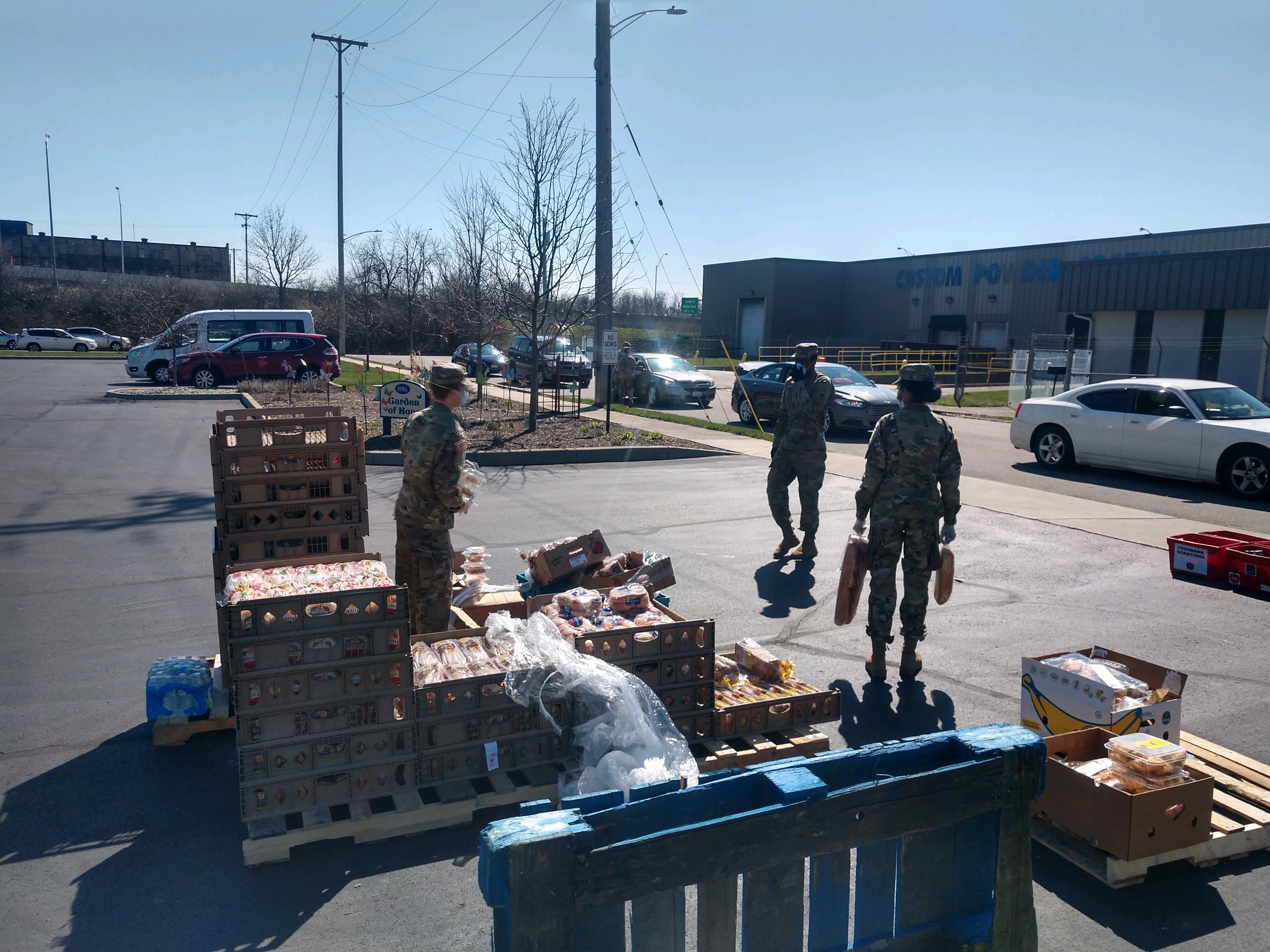 Soldiers hand supplies to cars curbside.